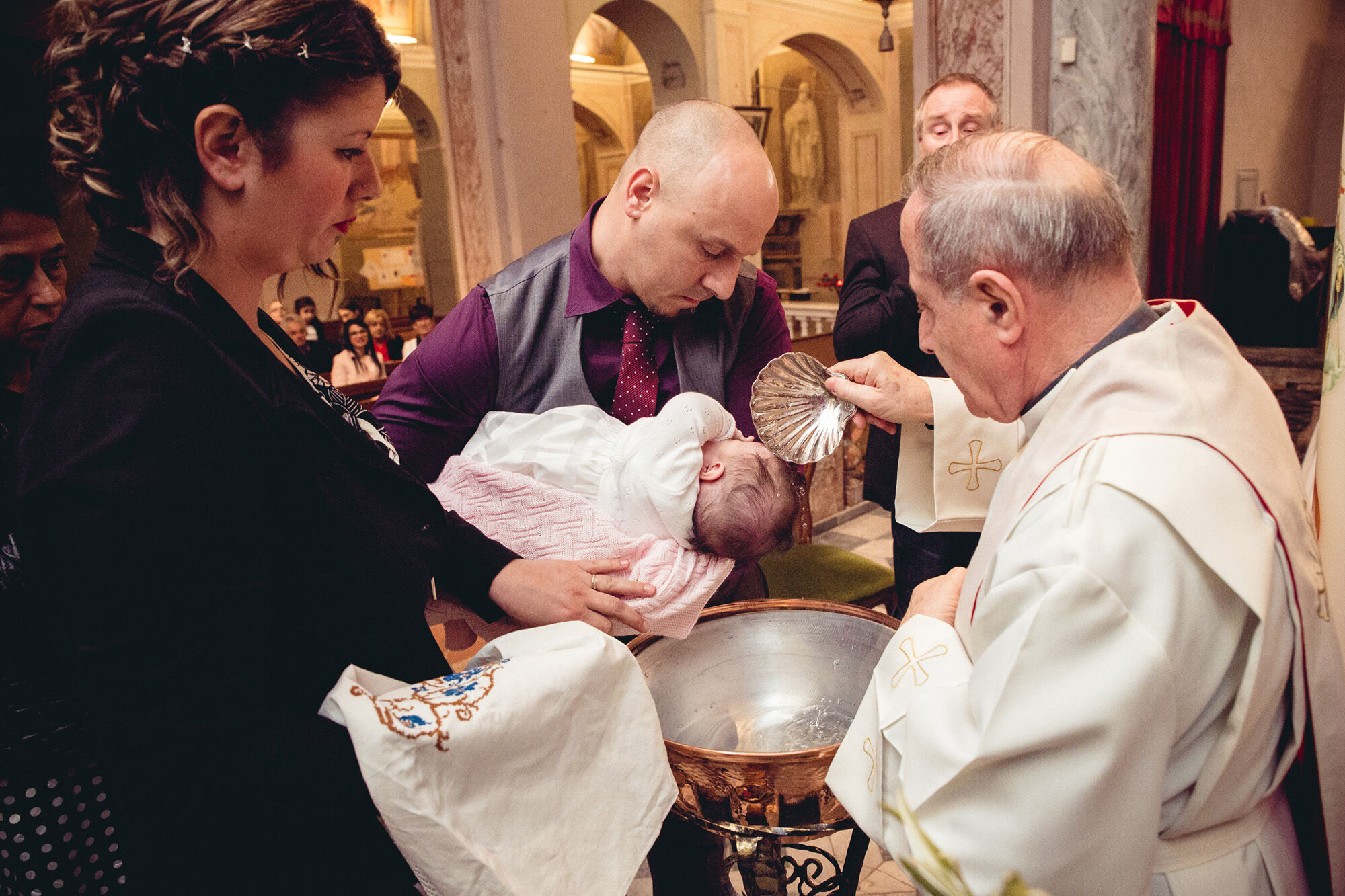Il momento dell'acqua al fonte battesimale con il sacerdote